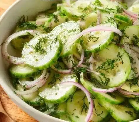 Fresh cucumber salad with herbs and dressing on a plate