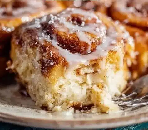 Freshly baked homemade cinnamon rolls topped with icing on a wooden table
