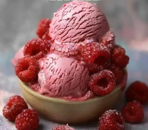 Creamy raspberry ice cream topped with fresh raspberries and mint leaves.