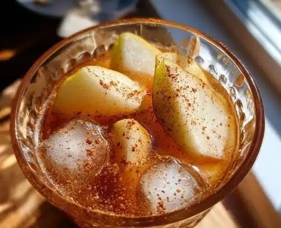 A refreshing Cinnamon Pear Cooler cocktail served in a glass with cinnamon sticks.