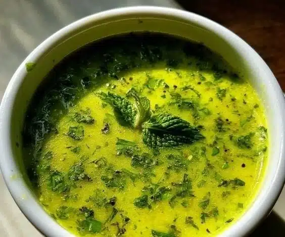 Bowl of Lemon Mint Vinaigrette drizzling over fresh garden salad