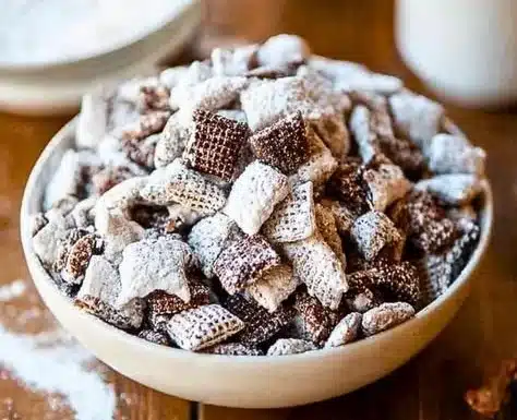 Bowl of Chunky Chex Mix Muddy Buddies with sweet and crunchy snacks
