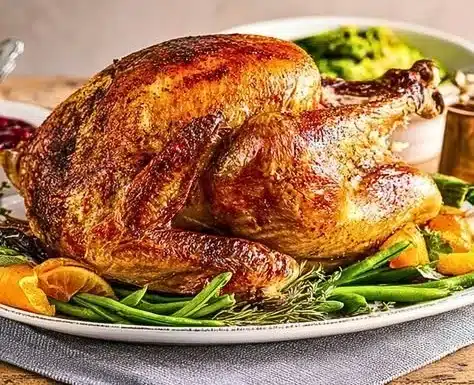 Perfectly roasted turkey garnished with herbs and vegetables on a serving platter.