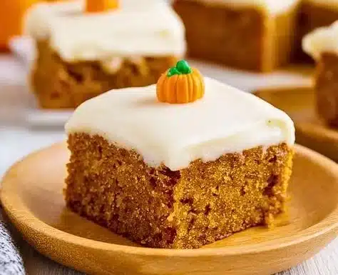 Pumpkin Bars with Cream Cheese Frosting 8 Delicious pumpkin bars topped with cream cheese frosting on a wooden table.