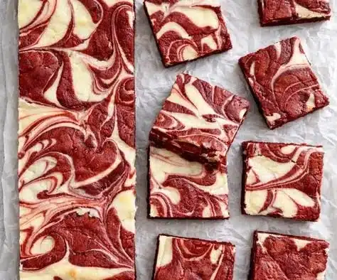 Delicious Red Velvet Cheesecake Brownies topped with creamy frosting